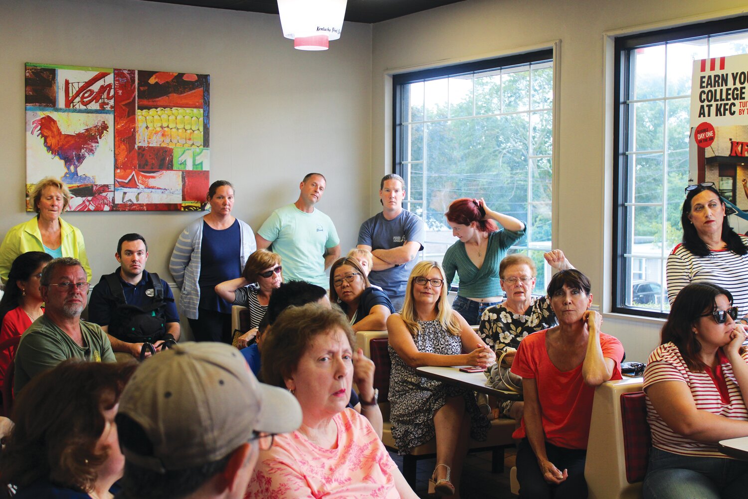 NEIGHBORS UNITED: A group of almost 40 neighbors who live behind the KFC on Reservoir Avenue pack into the restaurant’s small dining room ready to hear what the new owners have planned and how it may affect their lives. (Herald photo by Ed Kdonian)